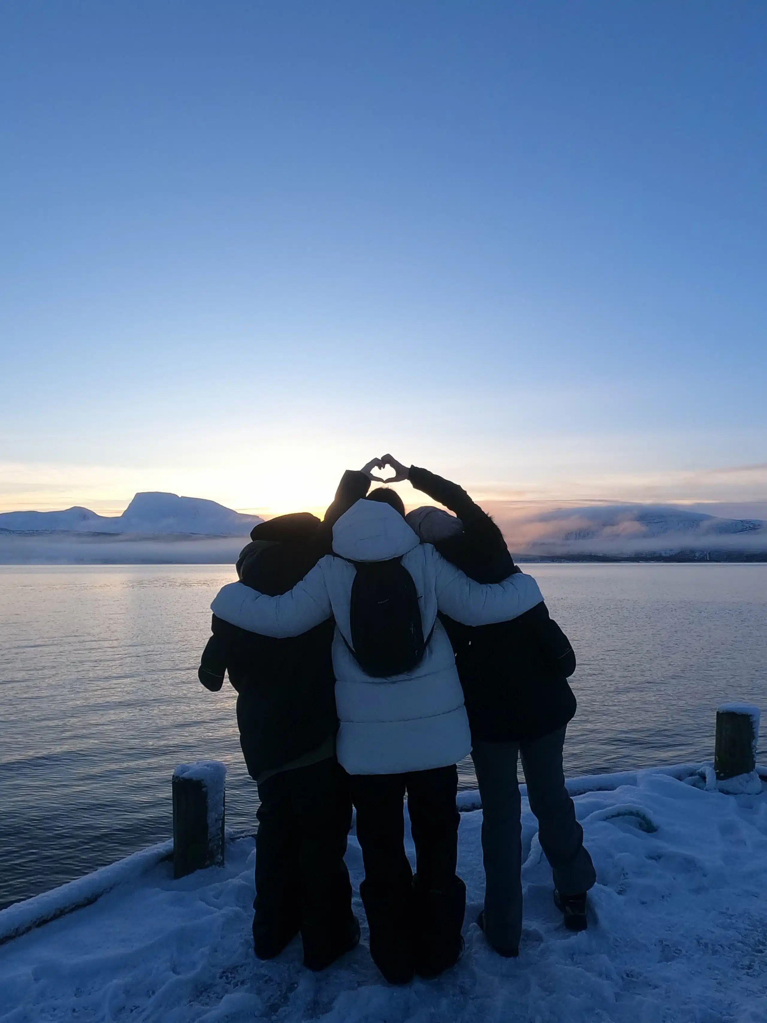 trois voyageuse faisant un coeur avec leur main dans la neige